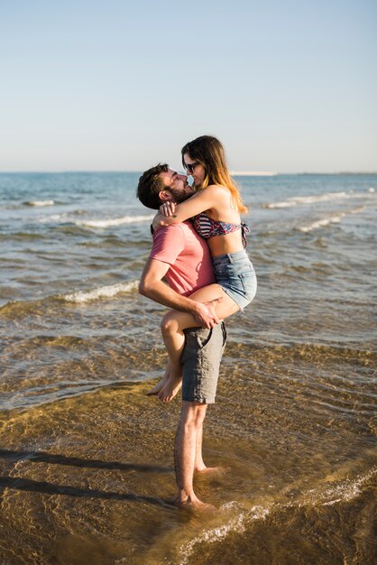 Романтическая молодая пара стоит возле моря на пляже