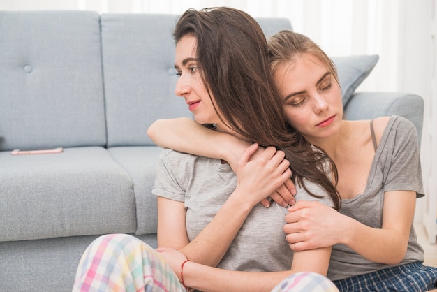 Romantic young lesbian couple near the grey sofa