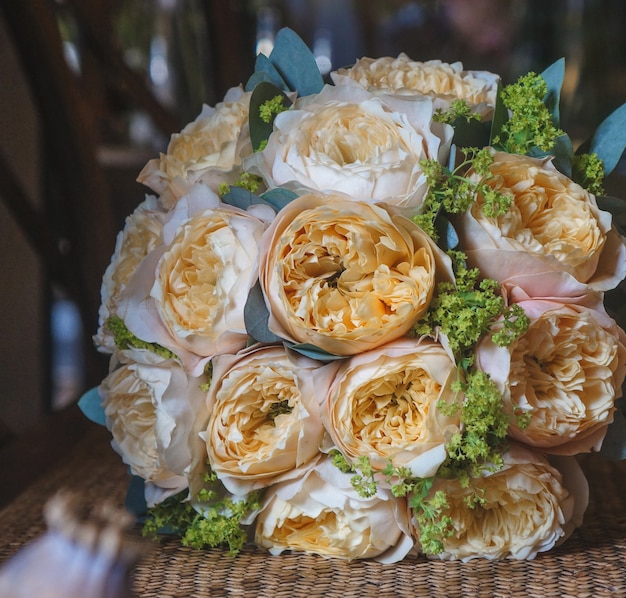 A romatic bridal bouquet of coral peonies standing on a bamboo table