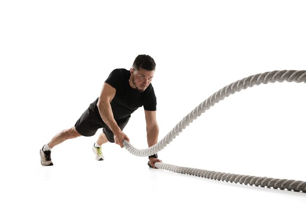 Ropes. Caucasian professional sportsman training on white studio.