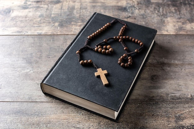 木製のテーブルの上の聖書のロザリオカトリックの十字架