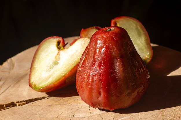 어두운 배경의 나무 탁자에 있는 장미 사과(syzygium jambos)