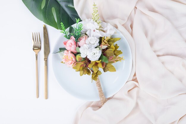 장미 꽃다발, 칼 붙이 및 흰색 표면에 접시.