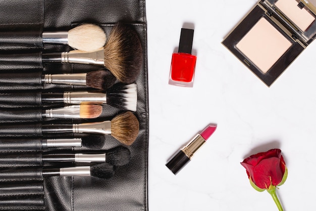 Rose and cosmetics near makeup brushes