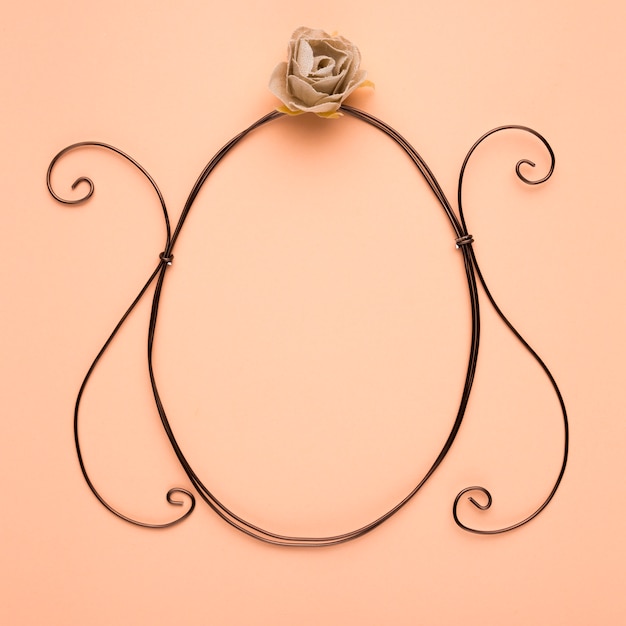 Free photo rose over the empty oval frame on peach backdrop