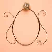 Free photo rose over the empty oval frame on peach backdrop