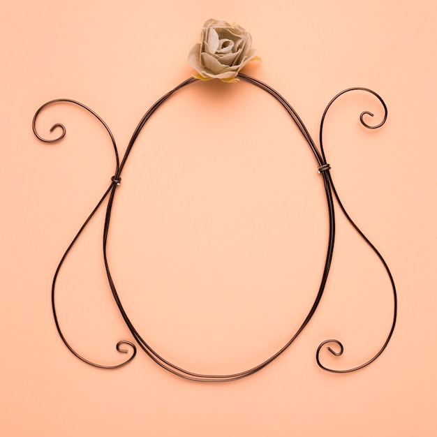 Rose over the empty oval frame on peach backdrop