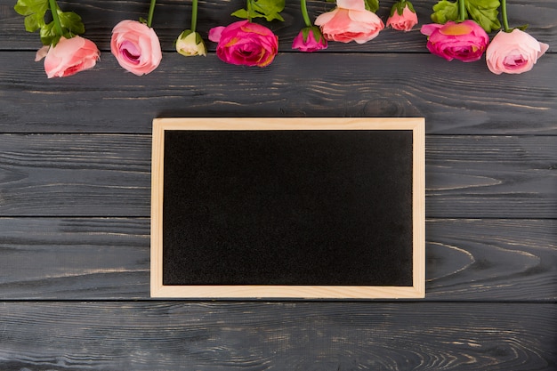 Rose flowers with big chalkboard on wooden table 
