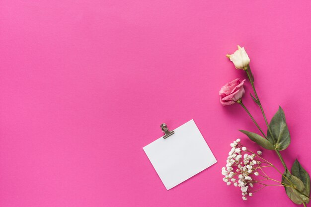 テーブルの上の空白の紙とバラの花