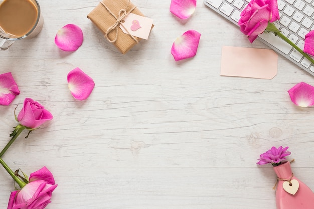 Розовые цветы с подарочной коробкой и клавиатурой на столе