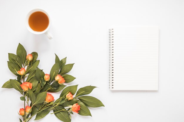 Rose flowers with notebook and tea cup