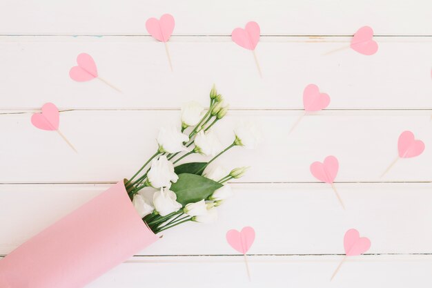 Розовые цветы с бумажными сердечками на столе