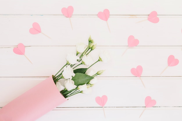 Rose flowers with paper hearts on table