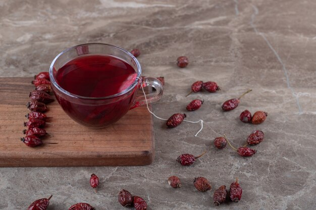 Rosehip tea ands rosehip fruit on the board, on the marble surface