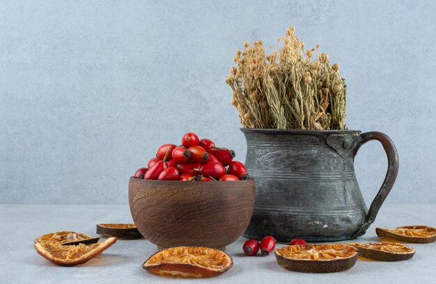 Rosehips, dried orange and rue on stone surface.