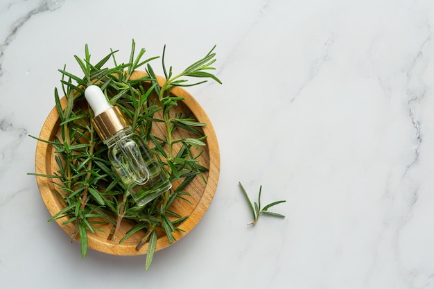 Free photo rosemary oil in bottle with rosemary plants