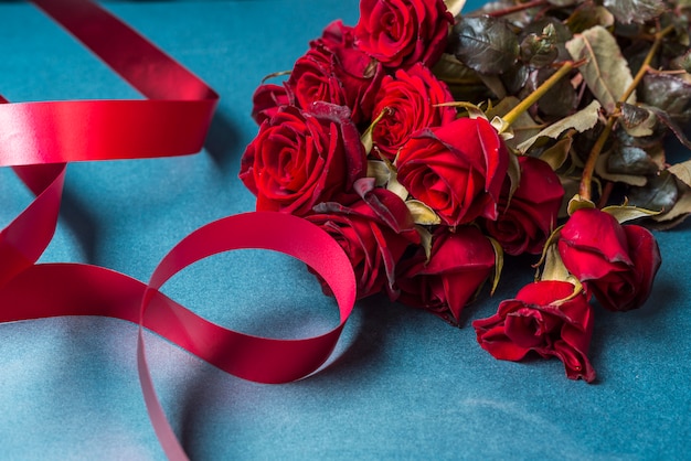 Free photo roses bouquet with red ribbon on table