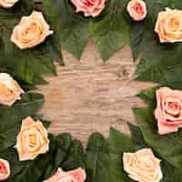 Free photo roses and green leaves on old wood background