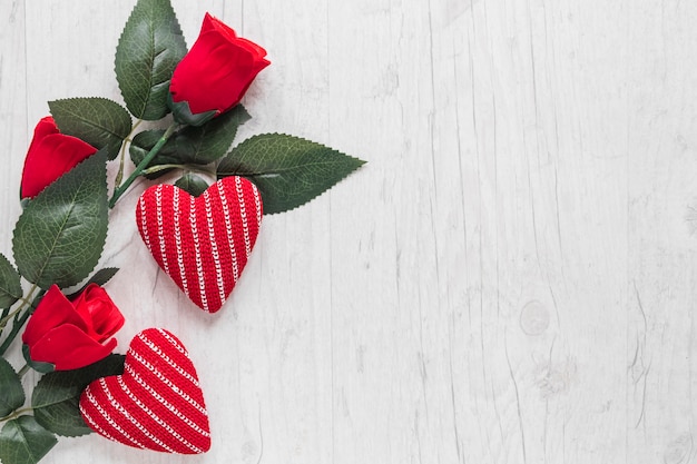 Roses and knitted hearts on wooden background