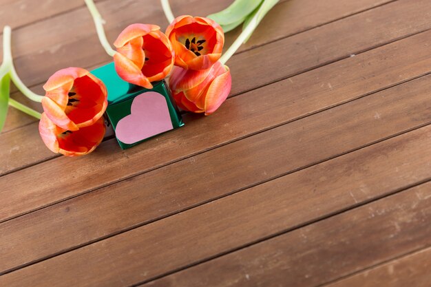 Roses and paper heart on wooden background