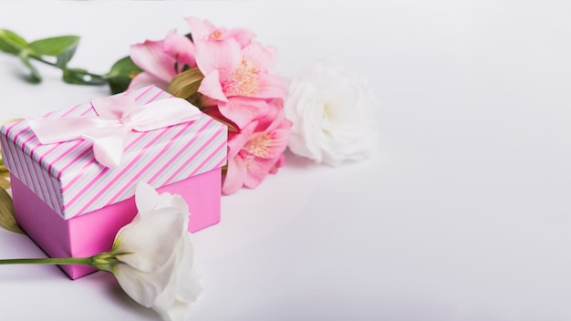 Roses and pink lily flowers with gift box on white background
