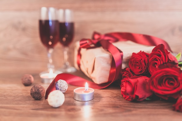 붉은 활과 선물을 가진 나무 테이블에 장미