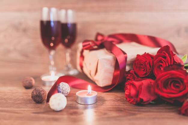 Roses on a wooden table with a gift with a red bow