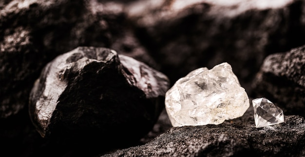 Необработанный алмаз рядом с ограненным алмазом в угольной шахте, концепция добычи и добычи полезных ископаемых Premium Фотографии
