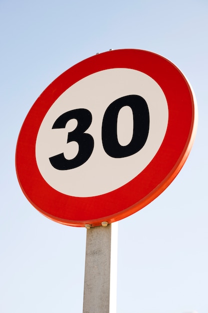 Бесплатное фото Круглый знак ограничения скорости 30 против голубого неба