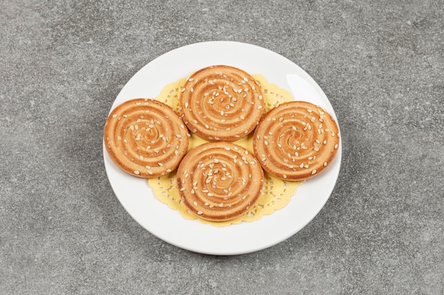 Round biscuits with sesame seeds on white plate