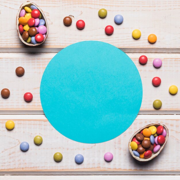 Round blue frame surrounded with colorful gems on wooden tabletop