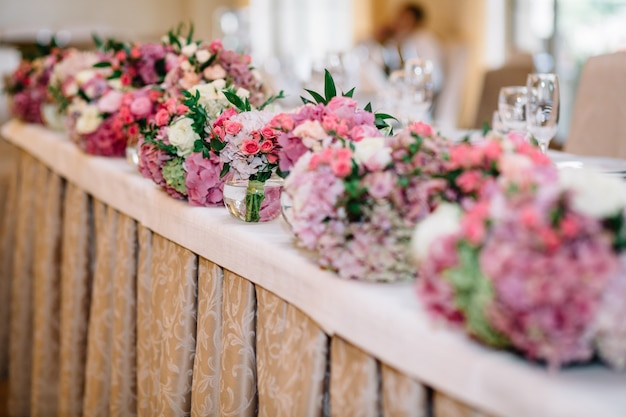 Round bouquets of pastel pink and green flowers stand on long di