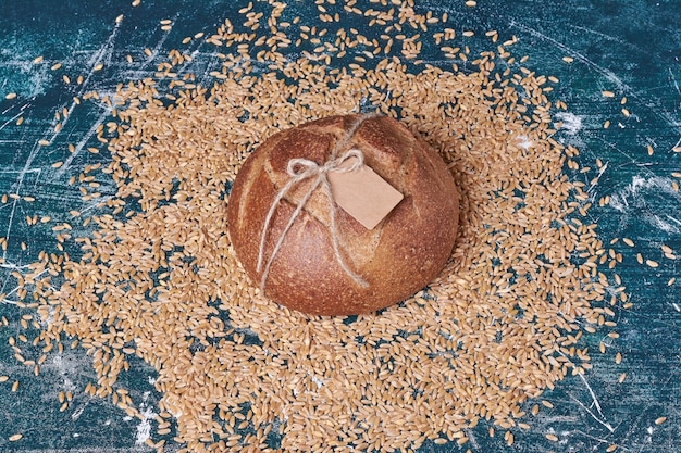 Круглый хлеб с пшеницей на синем столе.