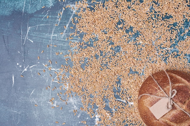 Free photo round bread with wheats on blue table.