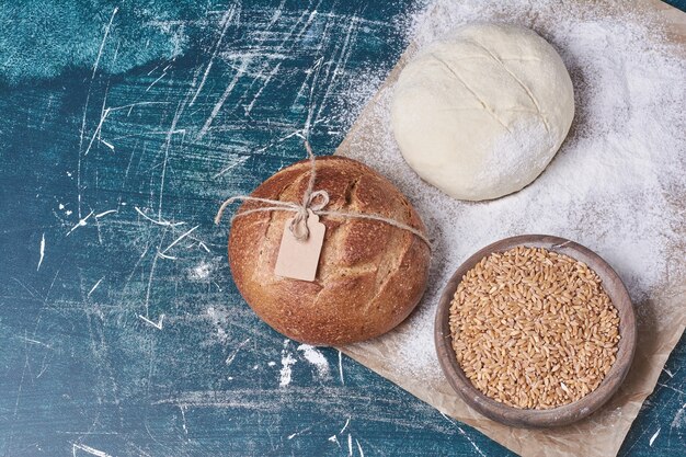 Wheats와 파란색 테이블에 반죽 라운드 빵.