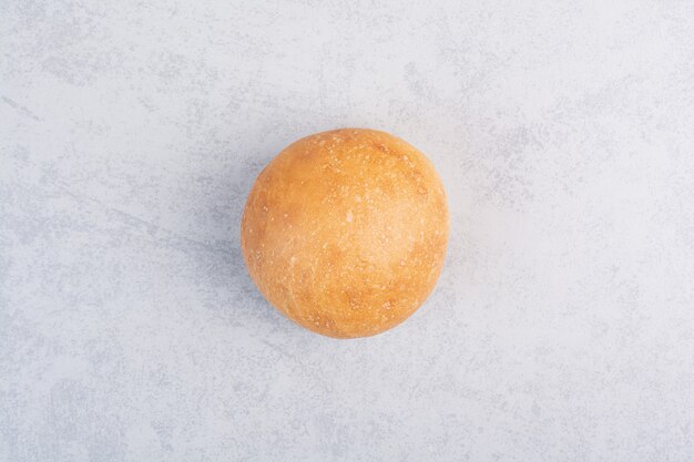 Round burger bun on stone surface