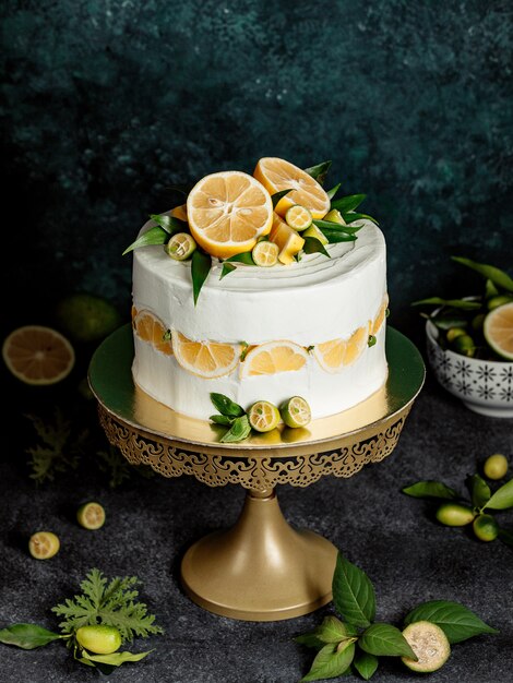 Round cake decorated with white cream, lemon and mint leaves