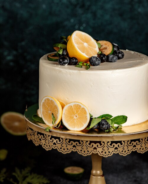 Круглый торт, украшенный белыми сливками и лимоном