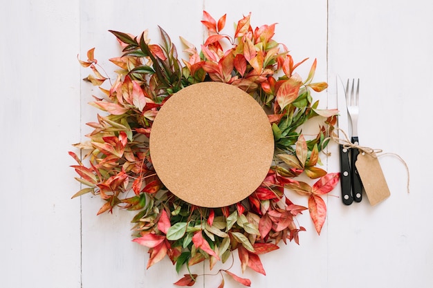 Free photo round cardboard and cutlery on autumn leaves