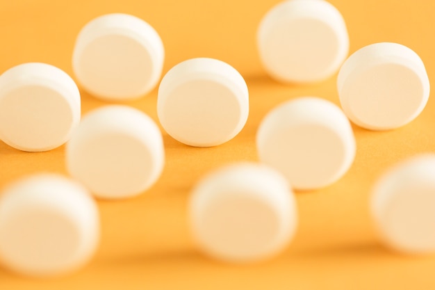 Round circular white pills standing on yellow background