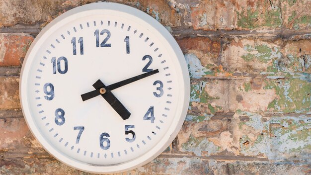 Round clock hanging on weathered brick wall