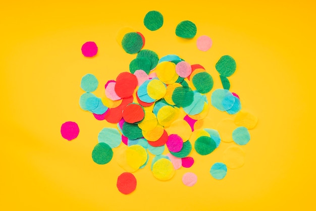 Round colorful confetti on yellow background