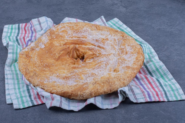 A round delicious pastry with sugar powder on a tablecloth