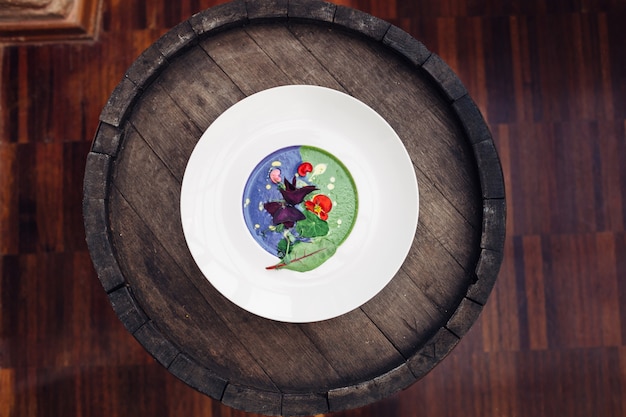 "Round dish with vegetables on barrel"