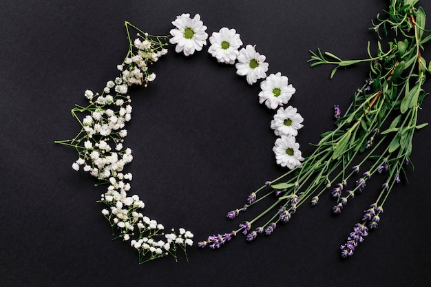 Cornice rotonda fatta di piccoli fiori bianchi su sfondo nero