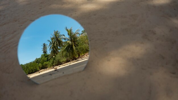 Round glass mirror at the beach reflecting landscape