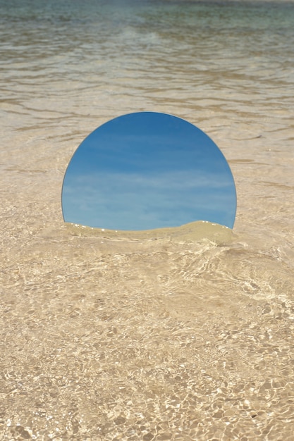 Round glass mirror at the beach reflecting landscape