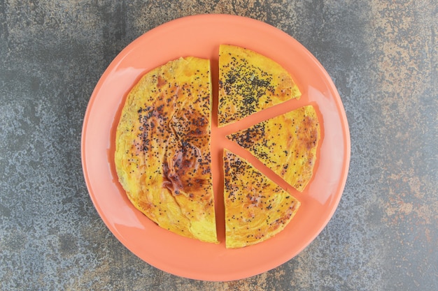 Free photo round pastry with poppy seeds on an orange plate