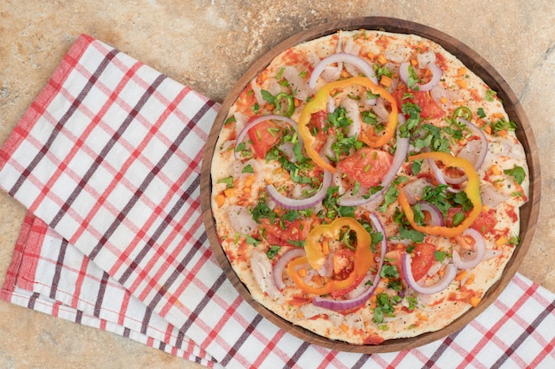 Round pita bread with peppers and onion on wooden plate.