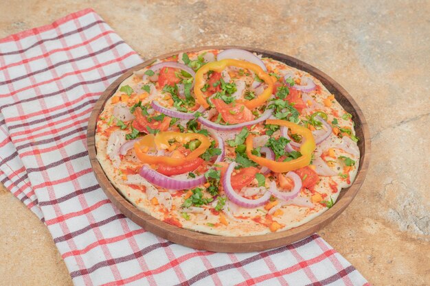 Round pita bread with peppers and onion on wooden plate